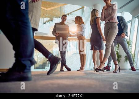 Employees are walking through the company building hallway in a relaxed manner. Business, people, company Stock Photo