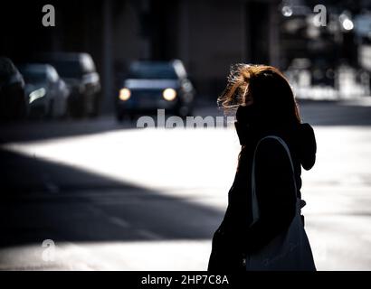 19 February 2022, Hessen, Frankfurt/Main: A woman crosses a street in downtown Frankfurt in windy and very sunny weather. Hesse survived the stormy night of low pressure 'Zeynep' without any problems. Photo: Frank Rumpenhorst/dpa Stock Photo
