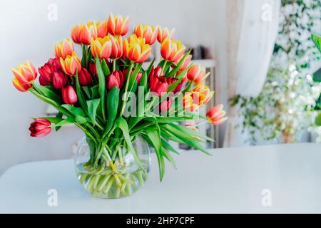 Huge spring colorful bouquet of tulips in vase on white table with ...