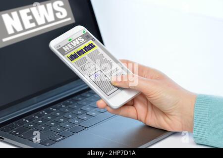 Closeup of young woman reading digital news on smart phone and laptop. Stock Photo