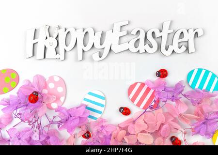 Colorful easter eggs and flowers. Border design with pink spring flowers. Happy easter text, greetings concept, holiday decoration background with cop Stock Photo
