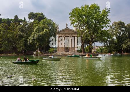 Rome, Italy, June 27, 2014:  Visitors of the gardens of the Villa Borghese in Rome, Italy, navigate rowboats near the Temple of Aesculapius during a s Stock Photo