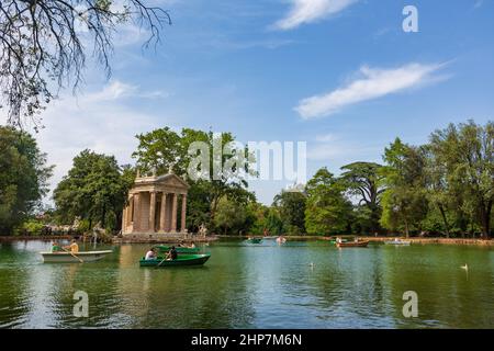 Rome, Italy, June 27, 2014:  Visitors of the gardens of the Villa Borghese in Rome, Italy, navigate rowboats near the Temple of Aesculapius during a s Stock Photo