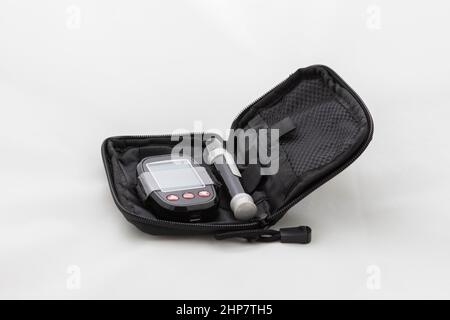 Set for measuring blood sugar. Measuring instrument and pen in a black case. Photo on a white background. Stock Photo