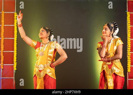 Young indian bharatanatyam dancers perfoming on stage with looking at stage - concept of professional traditional dancers and friendship Stock Photo