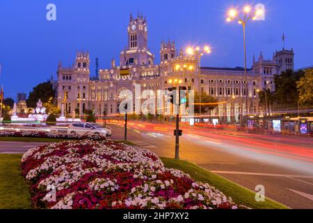 Madrid at Dusk - A dusk view of busy streets at Cybele Plaza in front of neo-classical style Madrid City Hall building - Cybele Palace. Madrid, Spain. Stock Photo