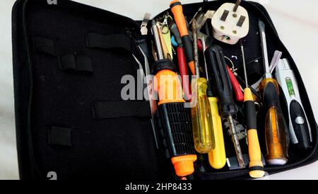 Close up of a tool bag with unsorted tools of tweezers, screwdrivers, pliers, 3-pin plug and others. Stock Photo