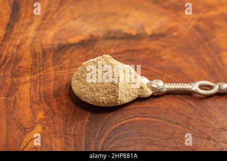 silver teaspoon full of grounded white pepper , on a wooden chopper Stock Photo