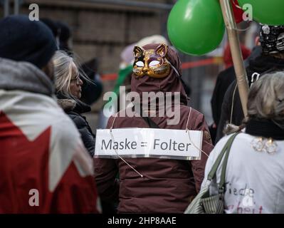19 February 2022, Hessen, Frankfurt/Main: A woman wears a mask on the back of her head and a placard reading 'Mask = Torture' at a demonstration of several thousand people against corona measures and mandatory vaccination in downtown Frankfurt. Photo: Frank Rumpenhorst/dpa Stock Photo