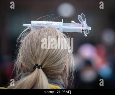 19 February 2022, Hessen, Frankfurt/Main: A woman carries a syringe on her head with the inscription 'My body, my property' during a demonstration of several thousand people against corona measures and compulsory vaccination in downtown Frankfurt. Photo: Frank Rumpenhorst/dpa Stock Photo