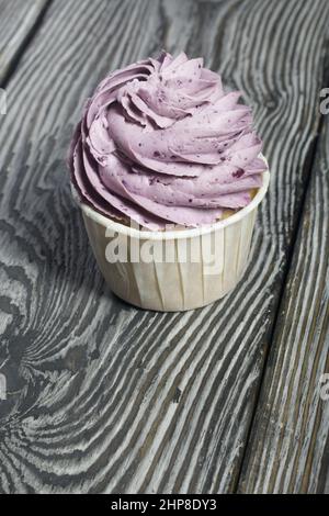 Cupcakes with cream and mascarpone. On pine boards. Close-up. Stock Photo