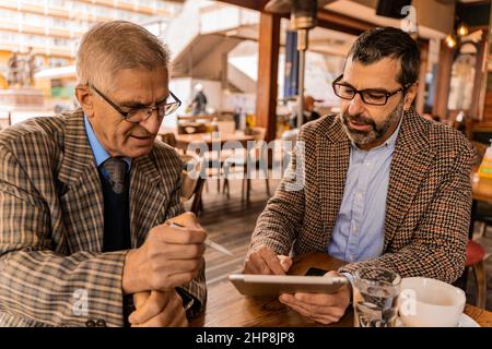 Two senior businessmen are having a discussion about the documents Stock Photo