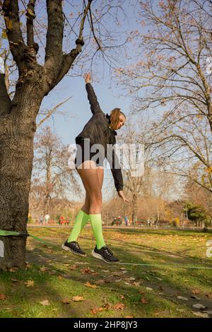 Attractive and beautiufl fit girl is balancing on the rope and smiling while having fun Stock Photo