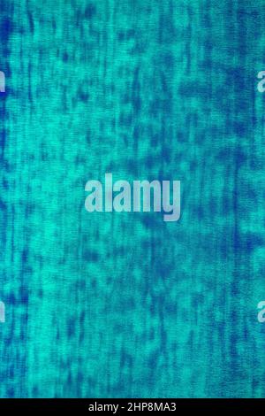 Close up of smooth surface of shiny metallic wrapping film with chameleon effect in electric green and blue colors and spotted pattern. Neon abstract Stock Photo