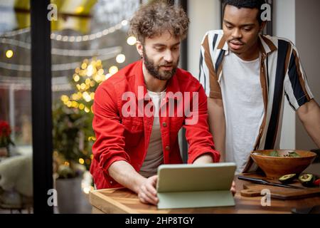 Two guys watching movie together on digital tablet at home Stock Photo