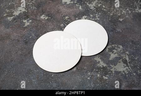 Photo of two blank white beer coasters on concrete background. Blank template for your design. Stock Photo