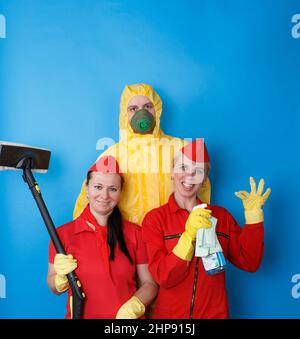 Cleaning company employees in work uniforms on an isolated blue background. Stock Photo
