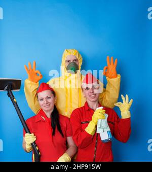 Cleaning company employees in work uniforms on an isolated blue background. Stock Photo