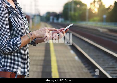 Woman using smart phone on railway station. Travelling in Europe by train. Stock Photo
