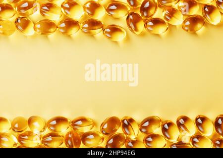 Capsules in a shell with fish oil on a yellow background and a place for text. Golden capsules with a biologically active supplement for health Stock Photo