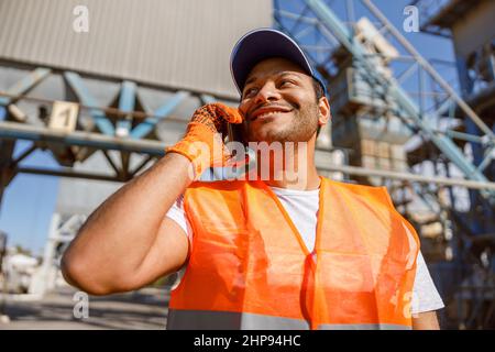 Multiethnic engineer talking on cellphone on construction site Stock Photo