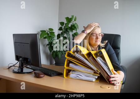 Overworked woman in the office with numerous paper files Stock Photo