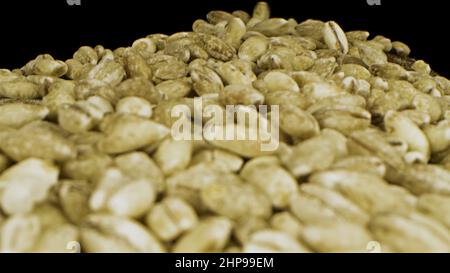 Close up of green coffee beans. Unroasted Arabian coffee beans falling down on black background, seeds for delicious hot drink preparation. Stock Photo