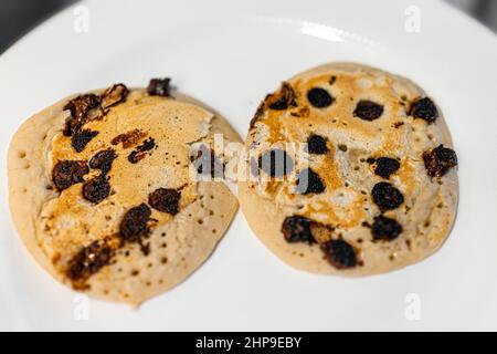 Macro closeup above view of two buttermilk dark chocolate chip pancakes on plate as traditional breakfast brunch dessert Stock Photo