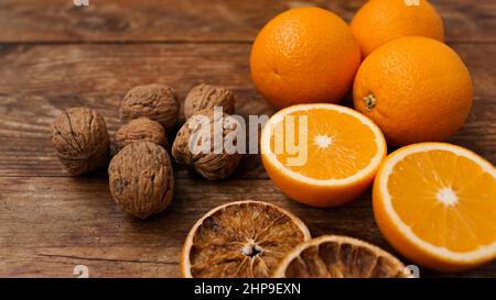 Oranges and walnuts on wooden background. Halves and dried oranges. Snack concept, mulled wine addition or autumn pie ingredients Stock Photo