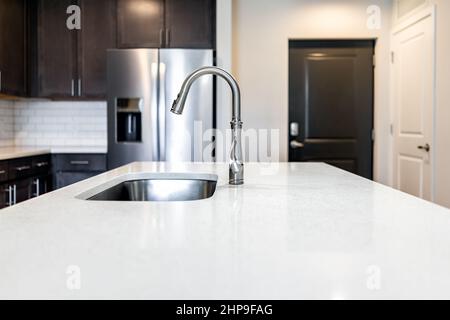 Kitchen room quartz countertop surface island in modern apartment home house by cabinets refrigerator fridge home appliance door entrance Stock Photo