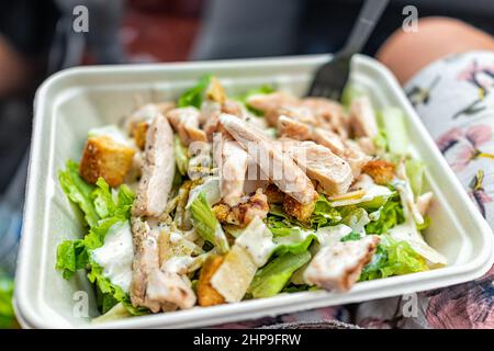 Closeup of fresh creamy caesar dressing salad with chopped vegetables romaine lettuce greens and grilled chickens strips in tray carton as quick fast Stock Photo
