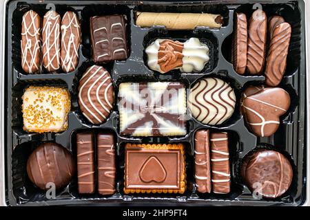 Box of European chocolates truffles gourmet milk white and dark sweets cookies package with different shapes variety flat top above view closeup Stock Photo