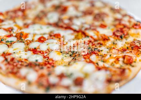 Small whole Italian homemade margherita pizza closeup macro side view with melted mozzarella cheese, red tomato sauce basil vegetable toppings and bok Stock Photo