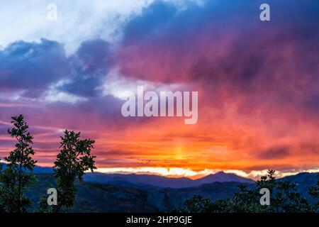 Wide angle view of colorful dramatic sunset twilight blue hour at Aspen, Colorado rocky mountains peak and vibrant orange color light in blue sky skys Stock Photo