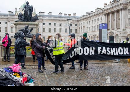 London, UK. 19th Feb, 2022. A security guard tries to stop the protesters from displaying their banner during the demonstration. Demonstrators gathered at the headquarter of British Fashion Council at the Somerset House to protest against the promotion of fast fashion by the London Fashion Week. The group later moved to protest outside the venues of the fashion show. Credit: SOPA Images Limited/Alamy Live News Stock Photo