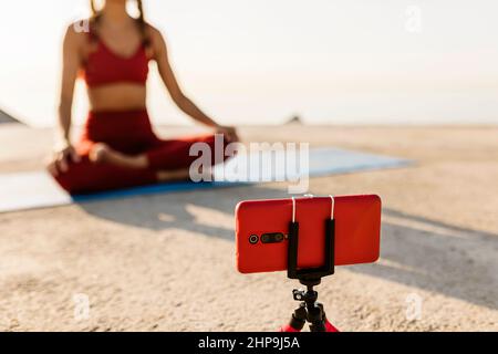Female instructor teaching online yoga lessons through video call on phone Stock Photo