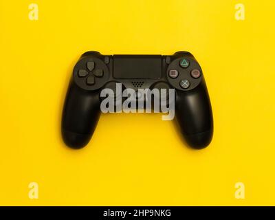 Black gaming controller isolated on yellow background. Stock Photo