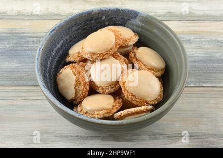 Vanilla and apricot macaron cookies also called holy belly buttons in ceramic snack bowl Stock Photo
