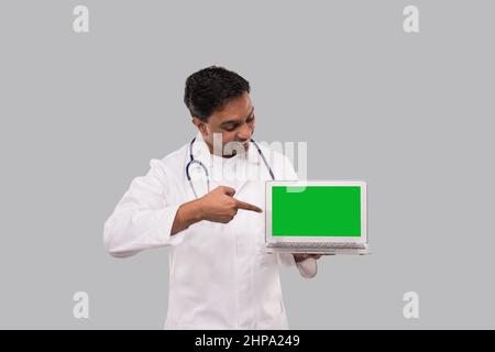 Doctor Pointing in Laptop Green Screen Isolated. Male Indian Doctor with Laptop in Hands. Stock Photo