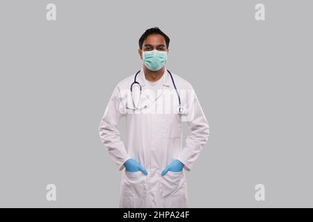 Male Doctor Wearing Medical Mask and Gloves Standing Isolated. Indian Man Doctor Medical Workwear. Medical Concept Stock Photo