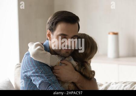 Peaceful grateful dad hugging little daughter girl with closed eyes Stock Photo