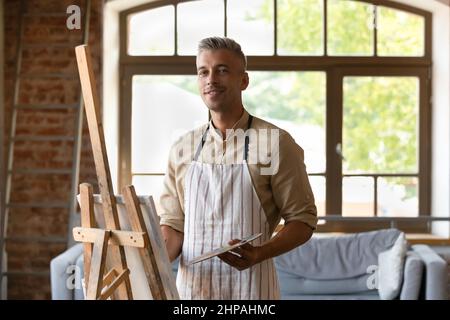 Portrait of handsome 40s man drawing on canvas. Stock Photo