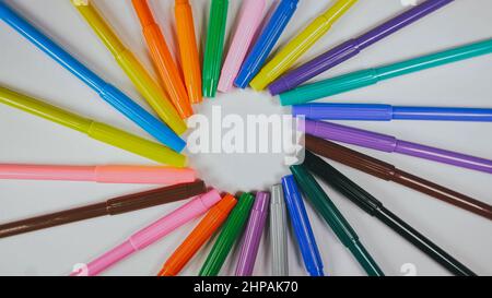 Many colored pencils are arranged around the edges of the image as a frame. In the center is an empty background with space for text. Mock up with copy space. Stock Photo