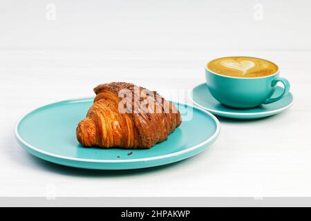 Croissant with chocolate and cup of coffee cappuccino on white wooden table. Stock Photo