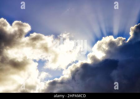 Dramatic sky with stormy clouds penetrated by rays of rising sun as silver lining. Stock Photo