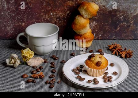 Muffins with coffee beans, star anise and fake flowers, next to an espresso cup Stock Photo