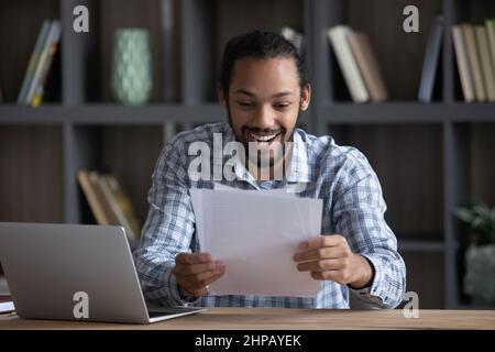 Amazed young African American man reading letter with good news. Stock Photo