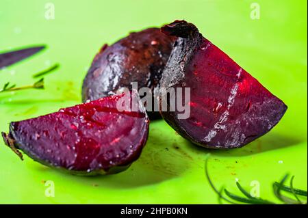 Three pieces of baked beetroot, closeup on green background. Stock Photo