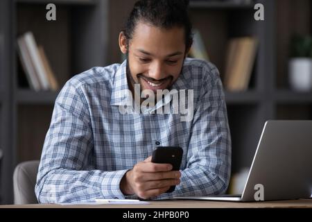 Happy handsome young African American man using mobile apps. Stock Photo