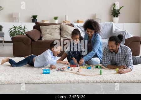 Joyful carefree relaxed African American family playing toys at home.